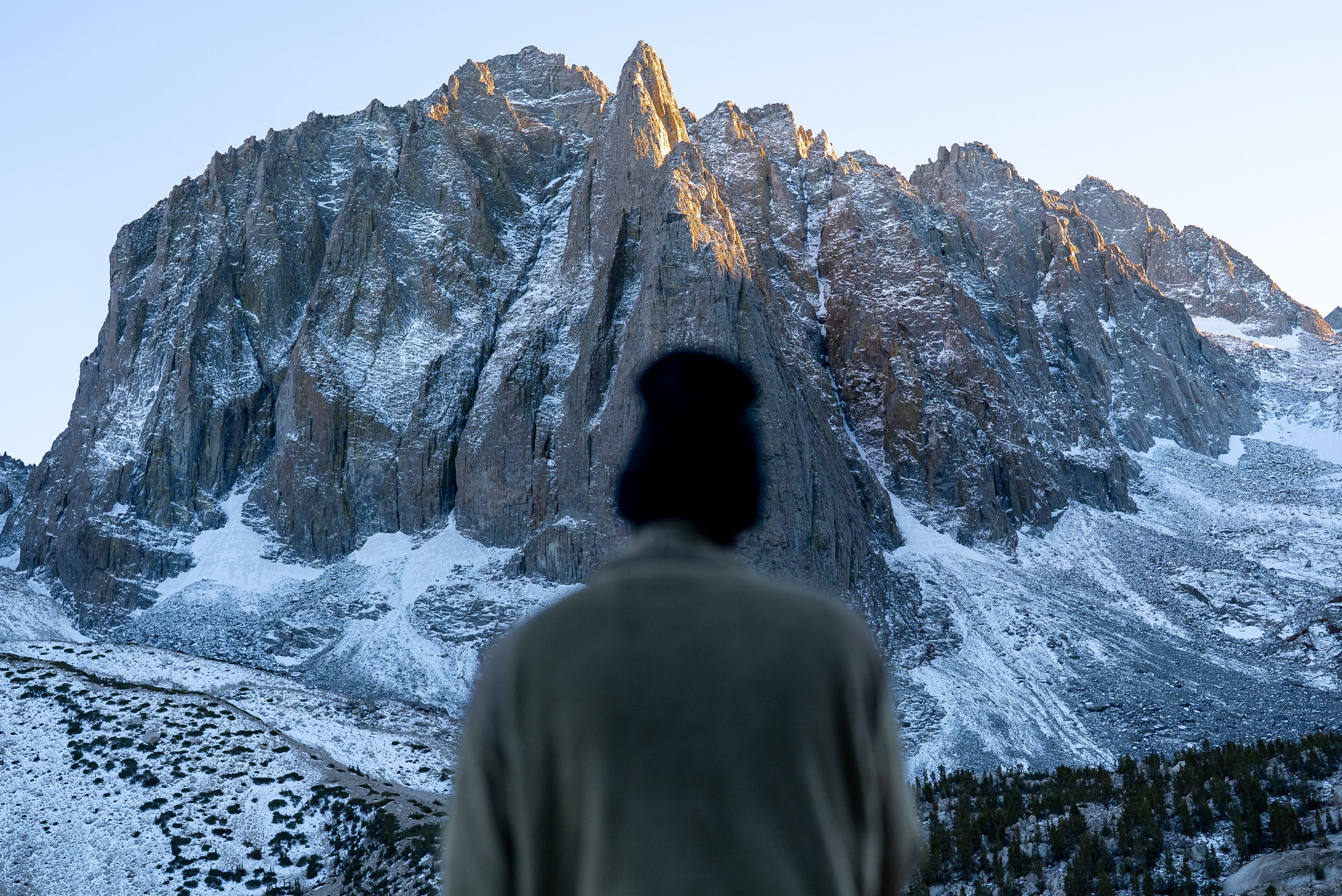 A figure looking toward a snow-dusted granite peak at first light, Big Pine, Sierra Nevada
